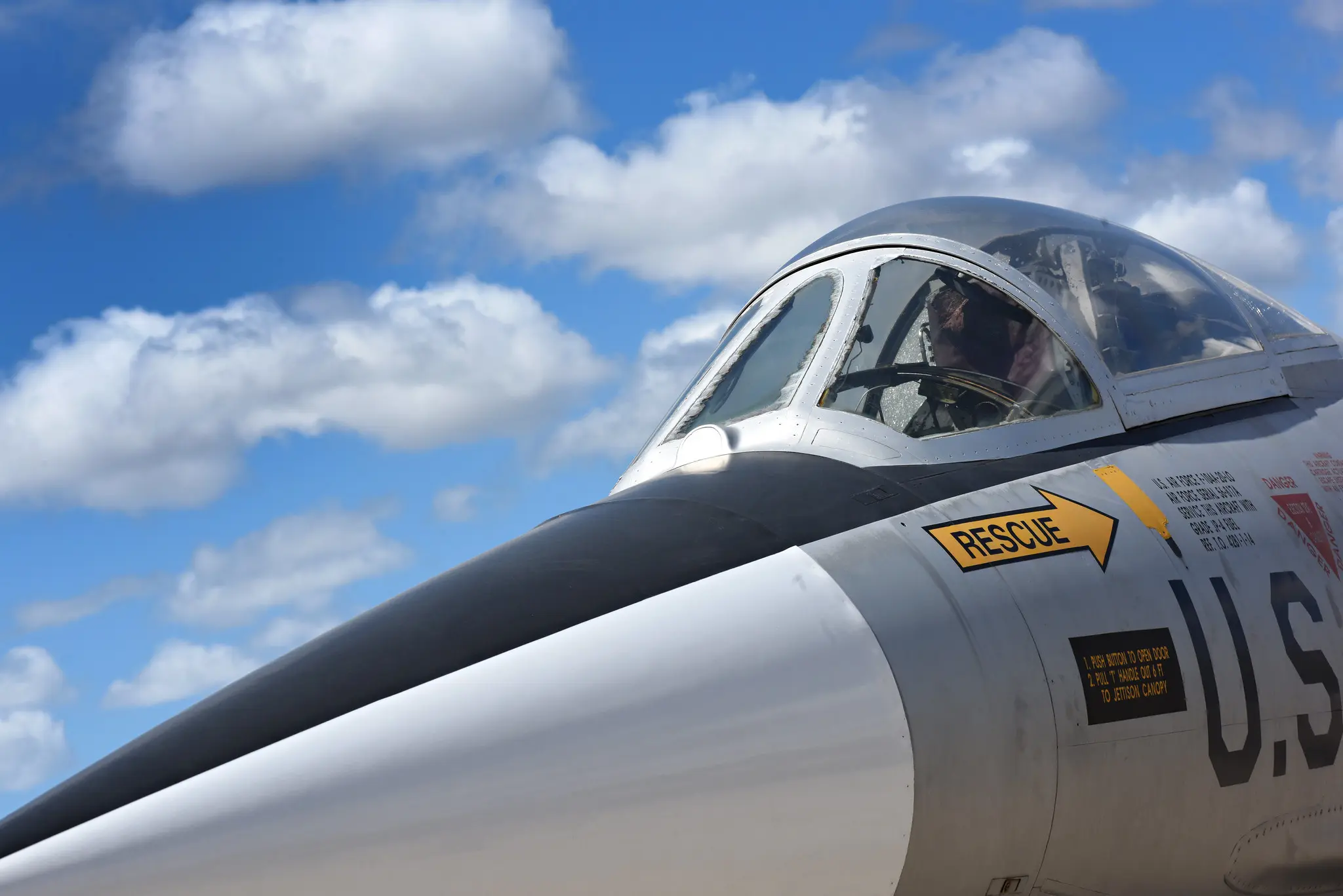 Close-up photograph of older fighter jet out on the runway on a clear, sunny day.